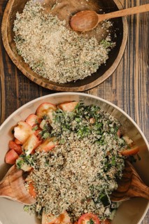A colorful salad made with fresh tomatoes, cucumber, greens, and a topping of chopped nuts in a