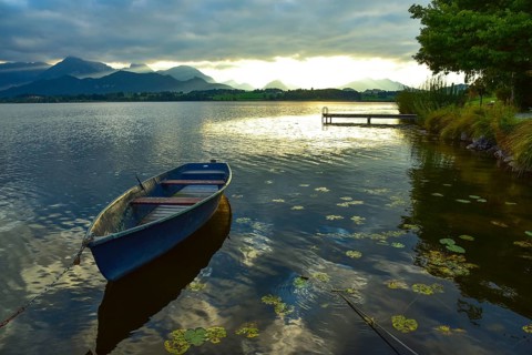 Rowing boat on Hopfensee in Allgäu at sunset in Hopfen am See, Bavaria, Germany