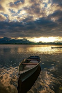 Rowing boat on Hopfensee in Allgäu at sunset in Hopfen am See, Bavaria, Germany