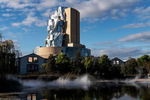 Front lake with artificial fog, Luma, 56 m high irregular tower designed by Frank Gehry, tower in