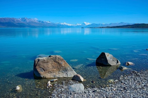 Large stones on clear lakeside with mountains in the background, Lake Pukaki Viewpoint, Pukaki,