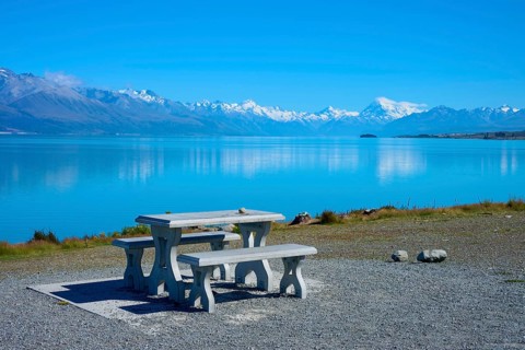 A lakeside picnic table with views of snow-capped mountains and calm water, Lake Pukaki Viewpoint,