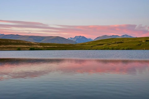 Calm lake with mountains and pink morning sky in the background, Lake McGregor, Tekapo, Canterbury,