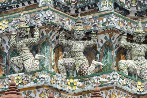 Demon figures (yaksha) supporting the central prang of Wat Arun decorated with colorful ceramic and