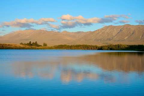 Evening over a calm lake with mountain range and beautiful cloud formation, Lake McGregor, Tekapo,