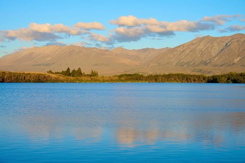 Extensive seascape in evening light with rolling mountains and cloudy skies, Lake McGregor, Tekapo,