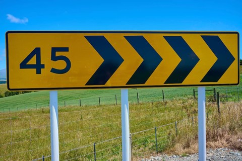 Road sign with arrows and number 45 in front of green landscape, Geraldine Fairlie Lookout,