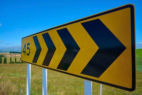 Yellow road sign with black arrows and number 45 on rural road, Geraldine Fairlie Lookout,