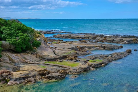 Rocky coastline on the blue sea with cloudy sky and calm water, Shag Point Lookout, Shag Point,