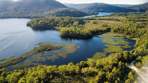 Dark lakes between the mountains of Tasmania on a sunny day, photograped with a drone