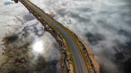 A long bridge over a shallow and calm lake on a cloudy day, photographed with a drone