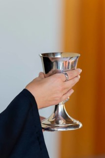 A pastor holds the chalice in both hands to present the drink during Holy Communion in Markt