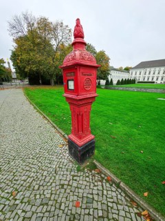Historic red fire alarm column on cobblestones on the roadside of the Federal President's office,