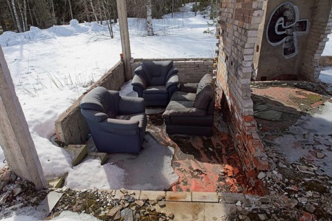 Furniture at burnt hotel frame made of concrete in spring with snow on the ground, Syvälampi,