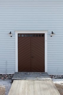 Closed old brown double doors with white frame and light blue board wall, Mustio, Finland