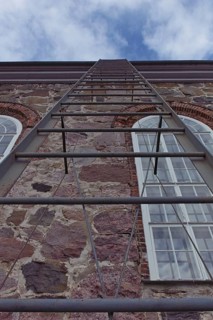 Metal ladder going up to the roof of a stone building, Karjalohja, Finland
