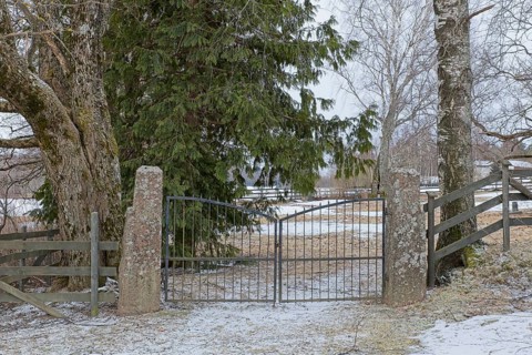 Closed old wrought iron gates mounted on stone gateposts to cemetery in winter, Degerby, Finland