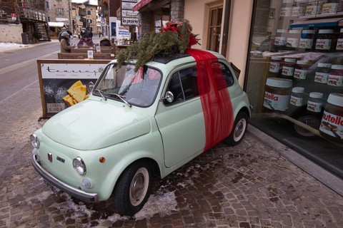 In Livigno in Lombardy in Italy, a small vintage Fiat, decorated as a Christmas present, stands in