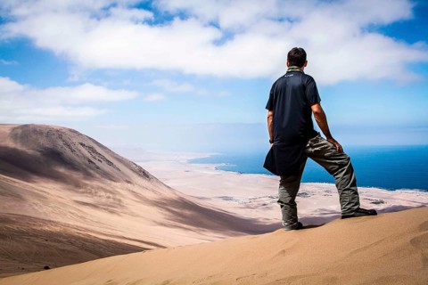 Young man looking at the view from Alto los Verdes, in Atacama Desert. Iquique, Tarapaca Region,
