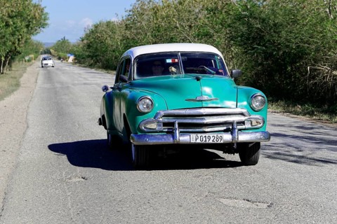 American classic car from the 1950s, near Holguin, Cuba, Vintage green car driving along a rural
