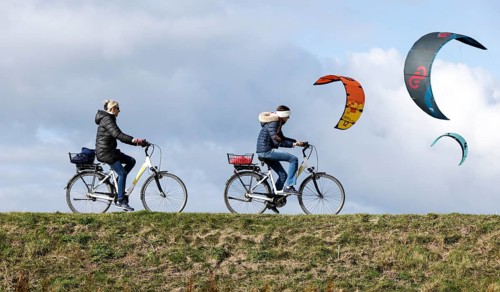 Cyclists ride across a dike and look at the sails of kite surfers, Fehmarn, 16.10.2025, Fehmarn,