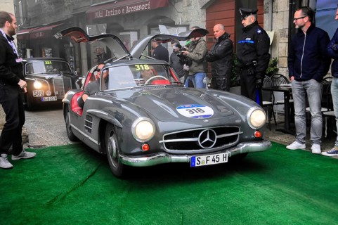 Dark gray 300 SL with open swing doors stops on the green carpet, surrounded by spectators and