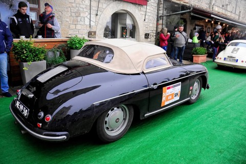 Black Porsche convertible with beige soft top drives relaxed through the old town at a classic car