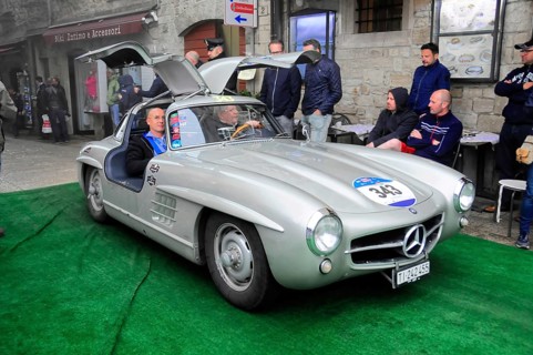 Silver 300 SL with open wing doors presents itself on the green carpet, interested audience in the