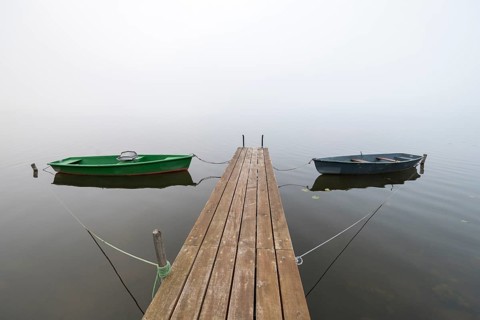 Two boats on a jetty on still, foggy water, Hopfensee, Ostallgäu, Bavaria, Germany