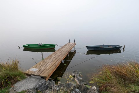 Boats and dock in foggy, quiet autumn landscape, Hopfensee, Ostallgäu, Bavaria, Germany