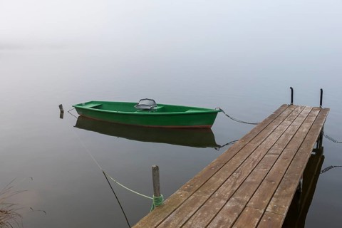 Single green boat on a wooden pier in fog, Hopfensee, Ostallgäu, Bavaria, Germany