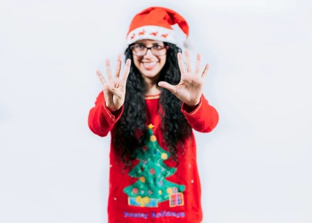 Happy girl in Christmas hat counting number NINE, isolated. Smiling girl in Christmas sweater