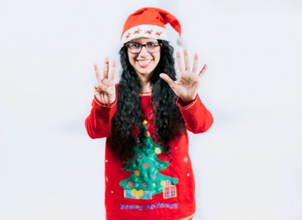 Happy girl in Christmas hat counting number EIGHT, isolated. Smiling girl in Christmas sweater