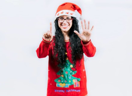Happy girl in Christmas hat counting number SIX, isolated. Smiling girl in Christmas sweater