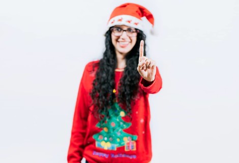 Happy girl in Christmas hat counting number ONE, isolated. Smiling girl in Christmas sweater
