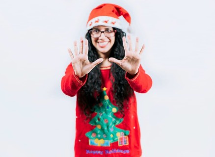 Happy girl in Christmas hat counting number TEN, isolated. Smiling girl in Christmas sweater