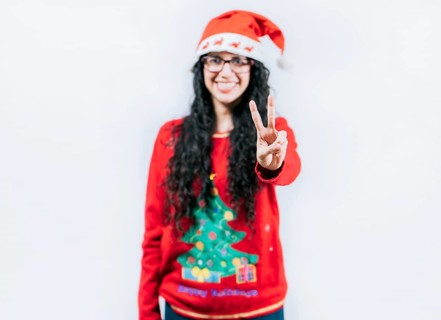 Happy girl in Christmas hat counting number two, isolated. Smiling girl in Christmas sweater