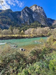 A fast-flowing river in an autumnal mountain landscape, surrounded by trees and rocks, Lienz
