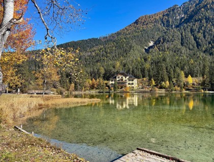 A lakeside villa surrounded by autumnal forests and clear reflection in the water, Lake Toblach,