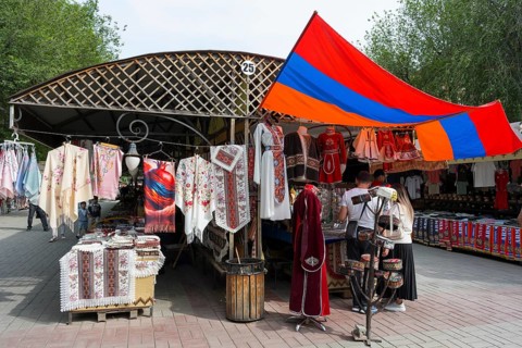 Market stand with traditional clothing and colorful textiles under the Armenian flag, Vernissage