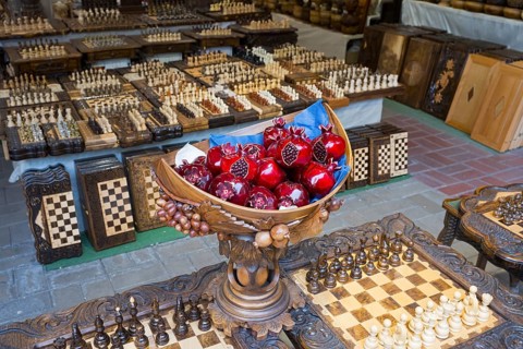 Colourful pomegranates in intricately carved wooden balls on checkerboards, Vernissage Market,