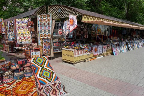 Carpet stand at a market with colorful patterns, cloths and souvenirs in an open setting,