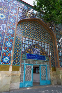 Colourful tiled wall with inscription and traditional pattern surrounds an entrance in a building,