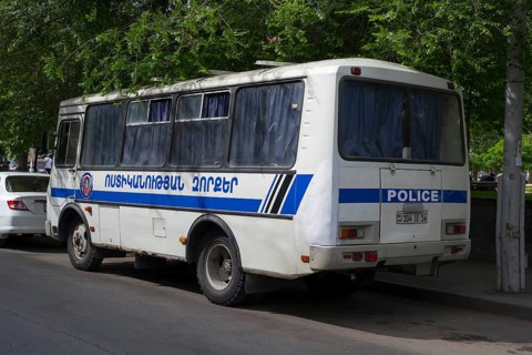 White police bus with Armenian lettering parked on the side of the road under shady trees, Yerevan,