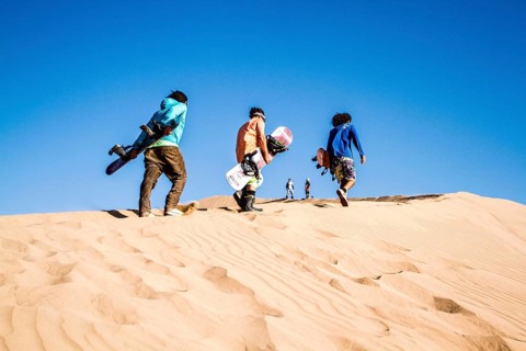 Sandboarding in Cerro Dragon, a sand dune located next to the city of Iquique, in Atacama Desert.