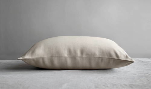 A side view of a beige pillow on a gray surface, emphasizing smooth fabric. AI generated