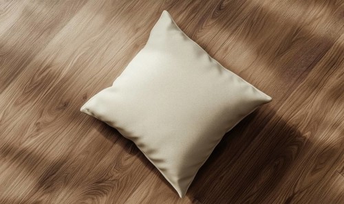 A cream pillow on a hardwood floor with natural light and shadows. AI generated