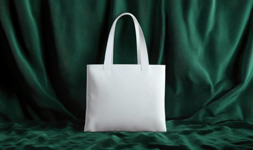 A white purse with a green background. The purse is sitting on a green cloth. The purse is white