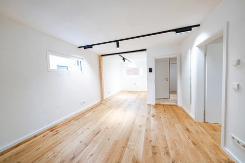 Bright living room with oak flooring and black track lights in a modern, reduced design, house