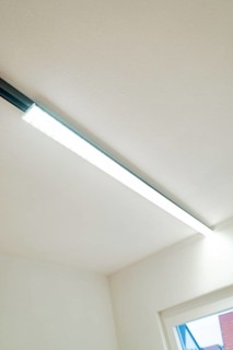 Slim LED light strip on white ceiling next to a window, clear and modern, house renovation, energy